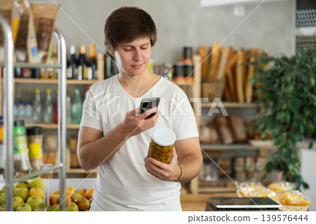 Male buyer scan pickled olives label in store 139576444