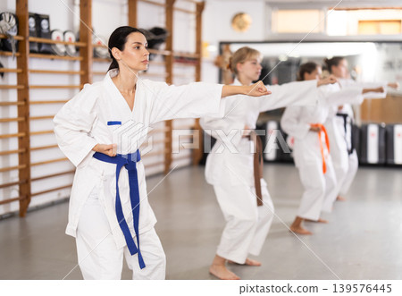 Young woman practicing punches standing in row with others Young woman practicing punches standing in row with others 139576445