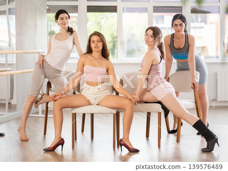 Young female dancers in stiletto heels posing on chairs in studio Young female dancers in stiletto heels posing on chairs in studio 139576489