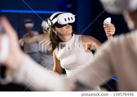 Expressive girl in VR goggles having fun in virtual reality room Expressive girl in VR goggles having fun in virtual reality room 139576498