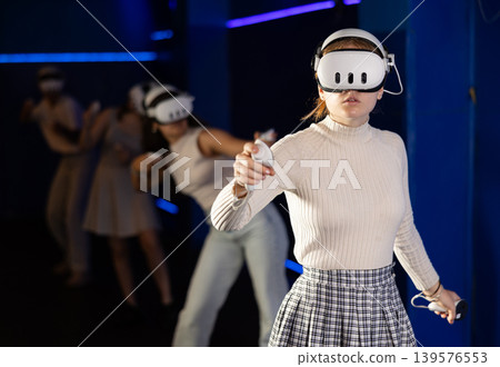 Young female in VR goggles playing virtual reality game 139576553