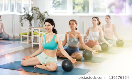 Teacher explains principle of performing body tilts and rests her hand on fitball Teacher explains principle of performing body tilts and rests her hand on fitball 139576564