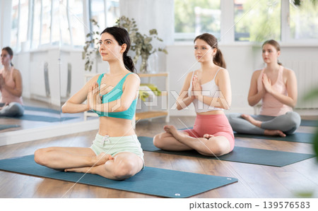 Meditation in lotus position during yoga class in studio. Women meditating Meditation in lotus position during yoga class in studio. Women meditating 139576583