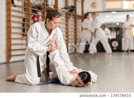 Women athletes in pair conduct training battle in oriental fighting technique judo Women athletes in pair conduct training battle in oriental fighting technique judo 139576610