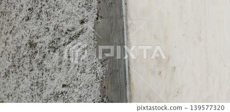 Close-up photo of a rough concrete wall texture combined with a smooth, light-colored plaster surface. Close-up photo of a rough concrete wall texture combined with a smooth, light-colored plaster surface. 139577320