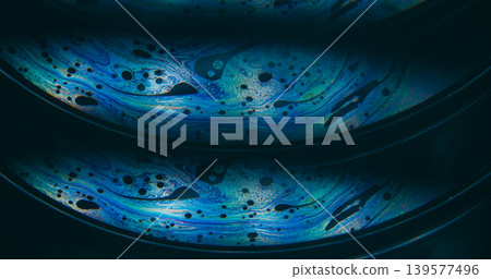 Dye water. Rainbow pollution. Blur blue purple green colorful chemical round oil water liquid leak on abstract dark black background. Dye water. Rainbow pollution. Blur blue purple green colorful chemical round oil water liquid leak on abstract dark black background. 139577496