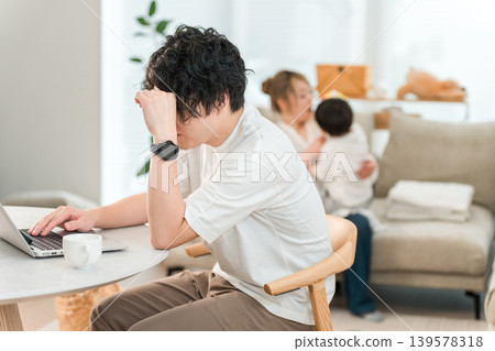 A male businessman working from home using his computer in the living room (troubled, frustrated, struggling, worried) A male businessman working from home using his computer in the living room (troubled, frustrated, struggling, worried) 139578318