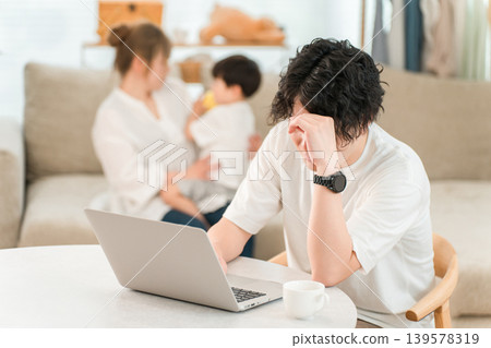 A male businessman working from home using his computer in the living room (troubled, frustrated, struggling, worried) 139578319
