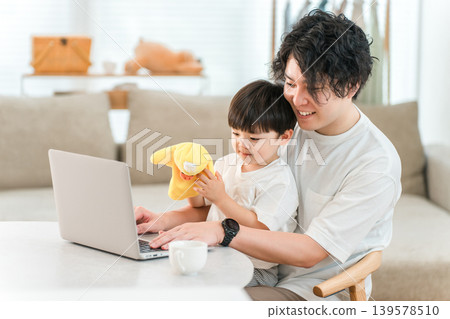 A parent and child spending time together in the living room while looking at a computer. A parent and child spending time together in the living room while looking at a computer. 139578510