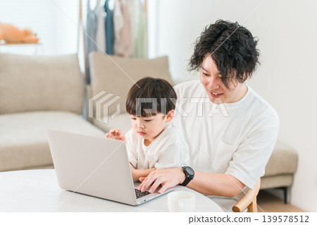 A parent and child spending time together in the living room while looking at a computer. A parent and child spending time together in the living room while looking at a computer. 139578512
