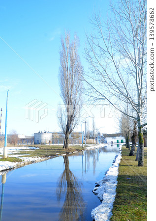 Winter canal landscape with bare trees and reflections Winter canal landscape with bare trees and reflections 139578662