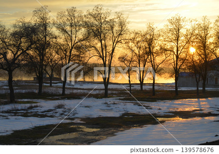 Winter sunset over snowy riverside trees Winter sunset over snowy riverside trees 139578676