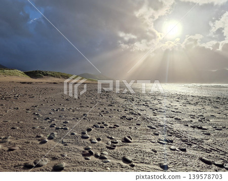 Stormy beach with sunlight breaking through clouds 139578703