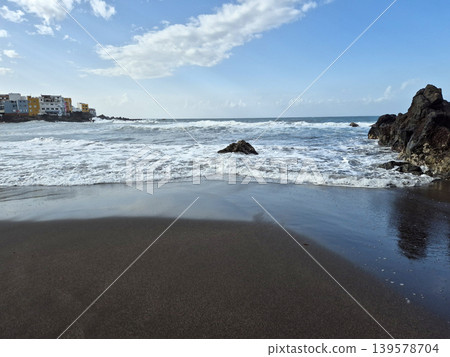 Waves washing onto a black sand beach 139578704