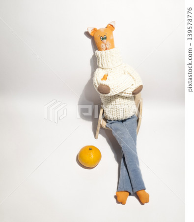 Handmade cat doll resting on chair with orange Handmade cat doll resting on chair with orange 139578776