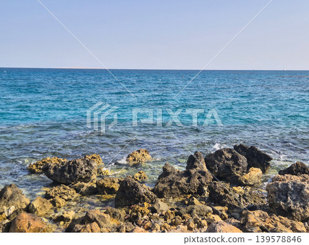 Rocky shoreline with calm blue sea Rocky shoreline with calm blue sea 139578846