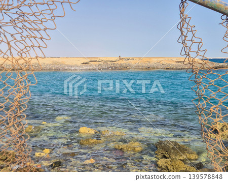 Rocky Seascape Framed by Rusted Fishing Net Rocky Seascape Framed by Rusted Fishing Net 139578848
