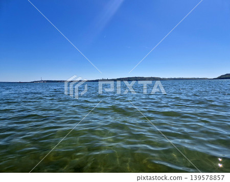 Calm blue sea with distant shoreline and clear sky 139578857