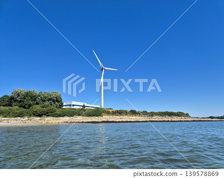 Wind Turbine on Coastal Shoreline Under Clear Sky Wind Turbine on Coastal Shoreline Under Clear Sky 139578869