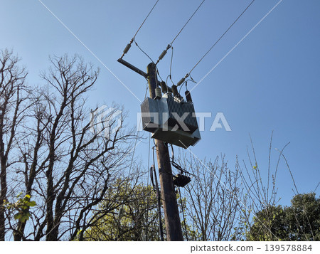 Utility pole with electrical transformer against blue sky 139578884
