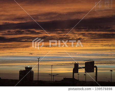 Dramatic sunset sky over silhouetted airport runway Dramatic sunset sky over silhouetted airport runway 139578898