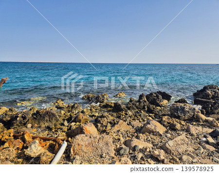 Rocky shoreline with calm blue sea and clear sky 139578925