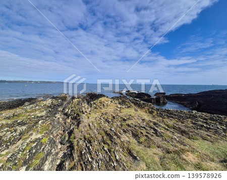 Rocky Coastal Shoreline Under Blue Cloudy Sky Rocky Coastal Shoreline Under Blue Cloudy Sky 139578926