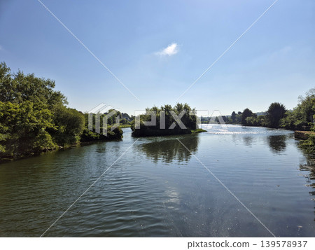 Serene river landscape with trees and blue sky 139578937