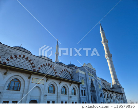 Grand mosque exterior with tall minarets against blue sky Grand mosque exterior with tall minarets against blue sky 139579050