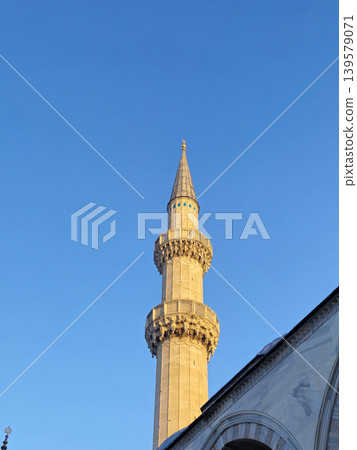 Tall mosque minaret against clear blue sky Tall mosque minaret against clear blue sky 139579071