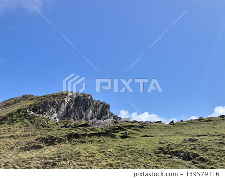 Rocky grassy hillside under clear blue sky Rocky grassy hillside under clear blue sky 139579116