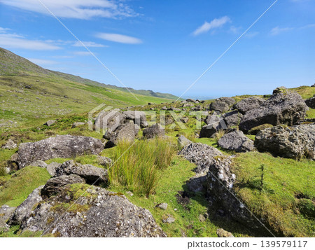 Rocky green hillside under a clear blue sky Rocky green hillside under a clear blue sky 139579117