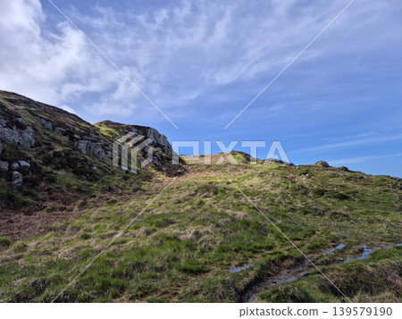 Grassy rocky hillside under dramatic blue sky 139579190