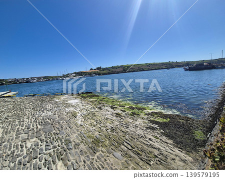 Sunny coastal harbor with stone slipway and calm water Sunny coastal harbor with stone slipway and calm water 139579195