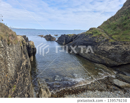 Rocky coastal inlet with calm sea and cloudy sky Rocky coastal inlet with calm sea and cloudy sky 139579238