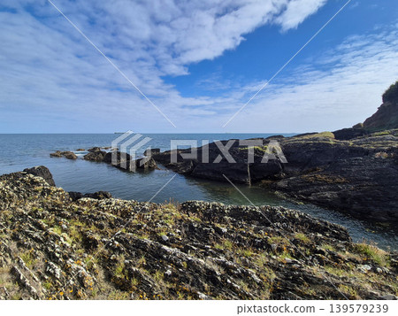 Rocky coastline with calm sea and cloudy sky Rocky coastline with calm sea and cloudy sky 139579239