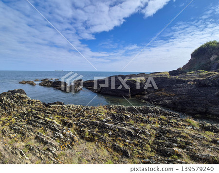 Rocky coastline with calm sea and cloudy sky 139579240