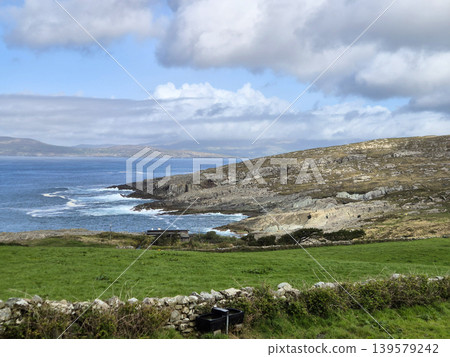 Rocky coastline with green field and cloudy sky Rocky coastline with green field and cloudy sky 139579242
