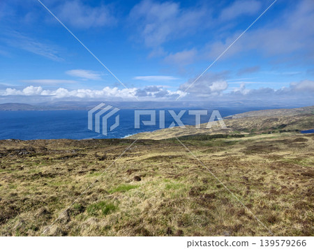 Coastal hillside overlooking blue ocean and cloudy sky 139579266