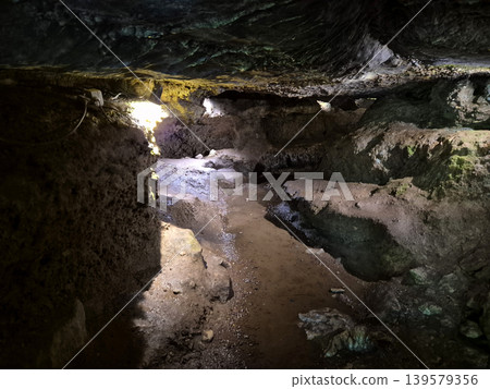 Narrow Cave Passage with Wet Rocky Floor 139579356