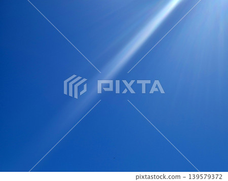 Bright blue sky with sun rays and lens flare Bright blue sky with sun rays and lens flare 139579372