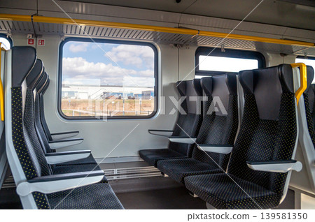 Train interior with empty seats and a view outside during daytime Train interior with empty seats and a view outside during daytime 139581350