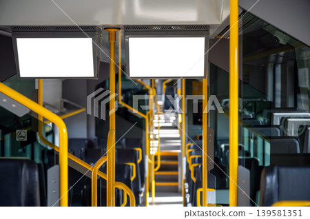 Blank interior view of a bus showing handles and empty seats during the day Blank interior view of a bus showing handles and empty seats during the day 139581351