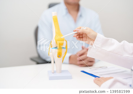 Doctor with Human Knee joint anatomy model. Osteoarthritis, Patellofemoral Pain Syndrome, Patellar Tendinitis, ACL, Anterior Cruciate Ligament, PCL, Posterior, MCL, Medial Collateral, LCL and Lateral 139581599