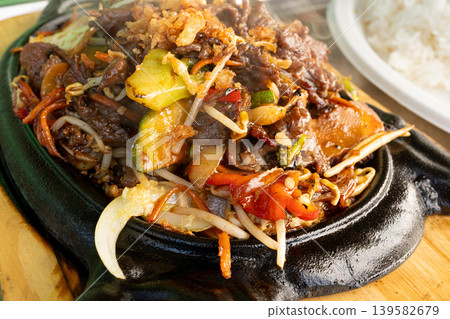 Sizzling beef fajita platter, asian beef stir fry in skillet closeup Sizzling beef fajita platter, asian beef stir fry in skillet closeup 139582679