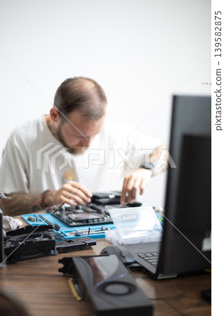 Man works on disassembling computer parts in a home office during the day to fix technical issues Man works on disassembling computer parts in a home office during the day to fix technical issues 139582875
