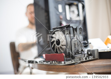 Person builds a computer at a table with parts and tools in a room during the day Person builds a computer at a table with parts and tools in a room during the day 139582933