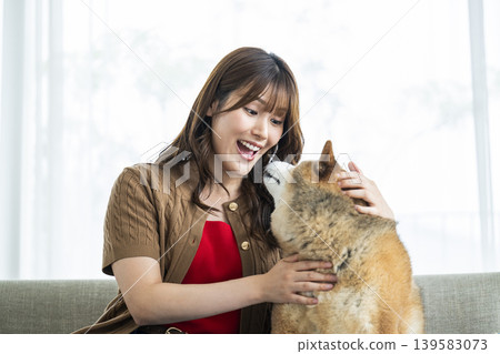 一位年輕女子正在撫摸一隻柴犬。 一位年輕女子正在撫摸一隻柴犬。 139583073