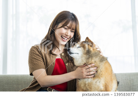 一位年輕女子正在撫摸一隻柴犬。 一位年輕女子正在撫摸一隻柴犬。 139583077