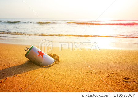 Crumpled beer can on sand beach at sea. Discarded broken can at seashore. Environmental pollution Crumpled beer can on sand beach at sea. Discarded broken can at seashore. Environmental pollution 139583307
